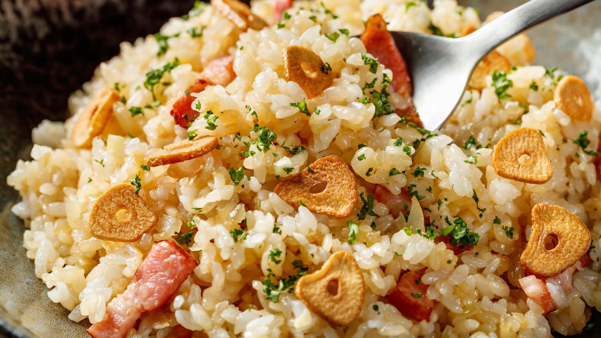 A bowl of rice topped with garlic chips and bacon.