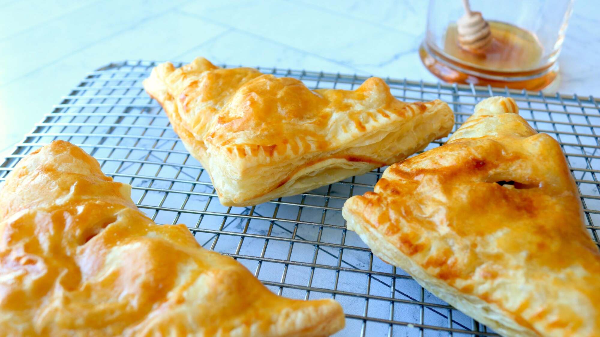 Apple turnovers sit on a wire cooling rack.