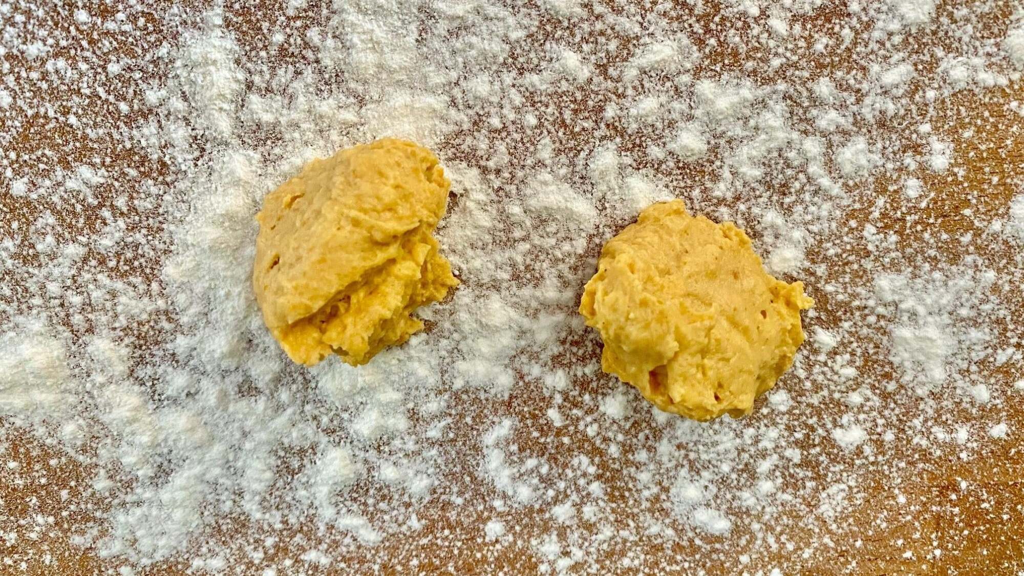 Two spoonfuls of gnocchi dough on a floured table.