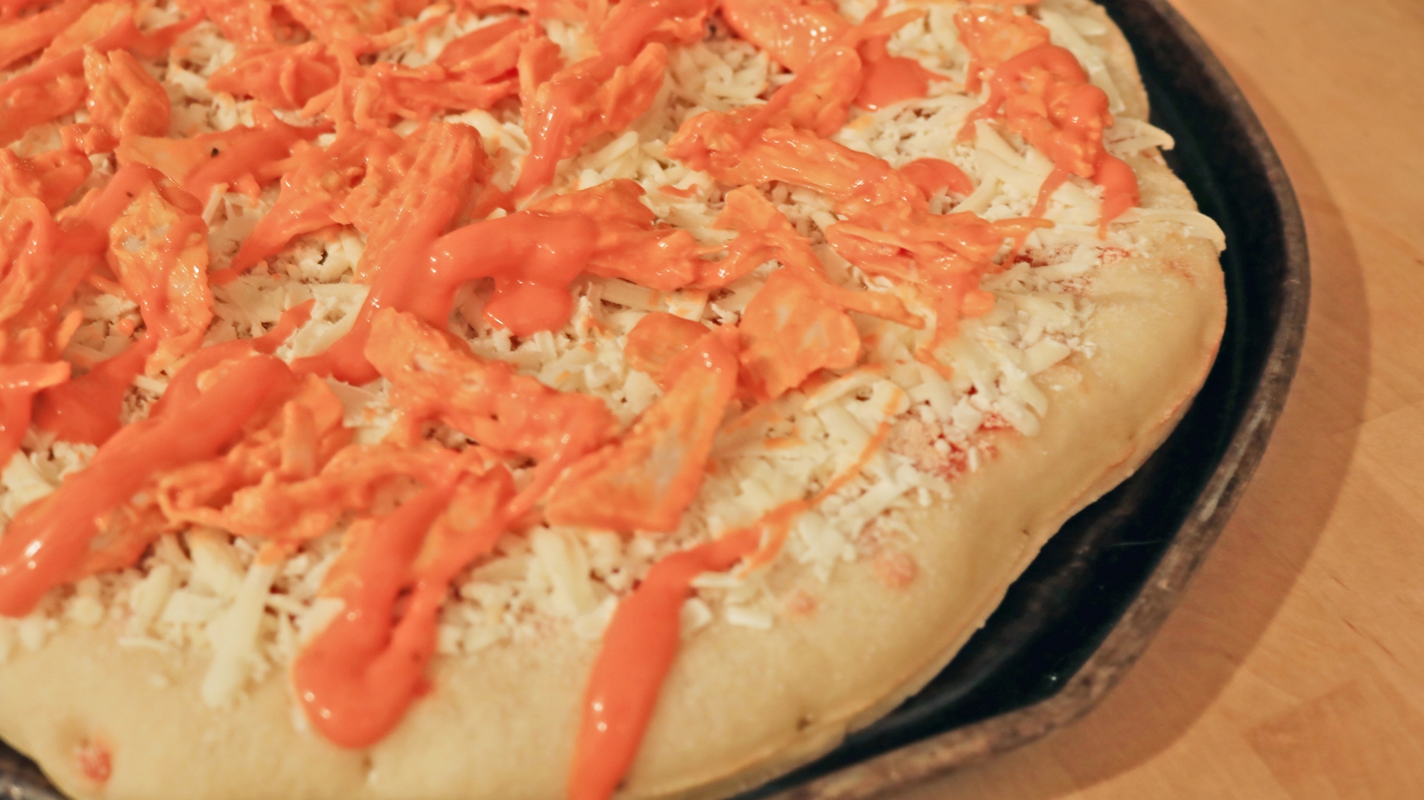 A frozen pizza with buffalo sauce on it.