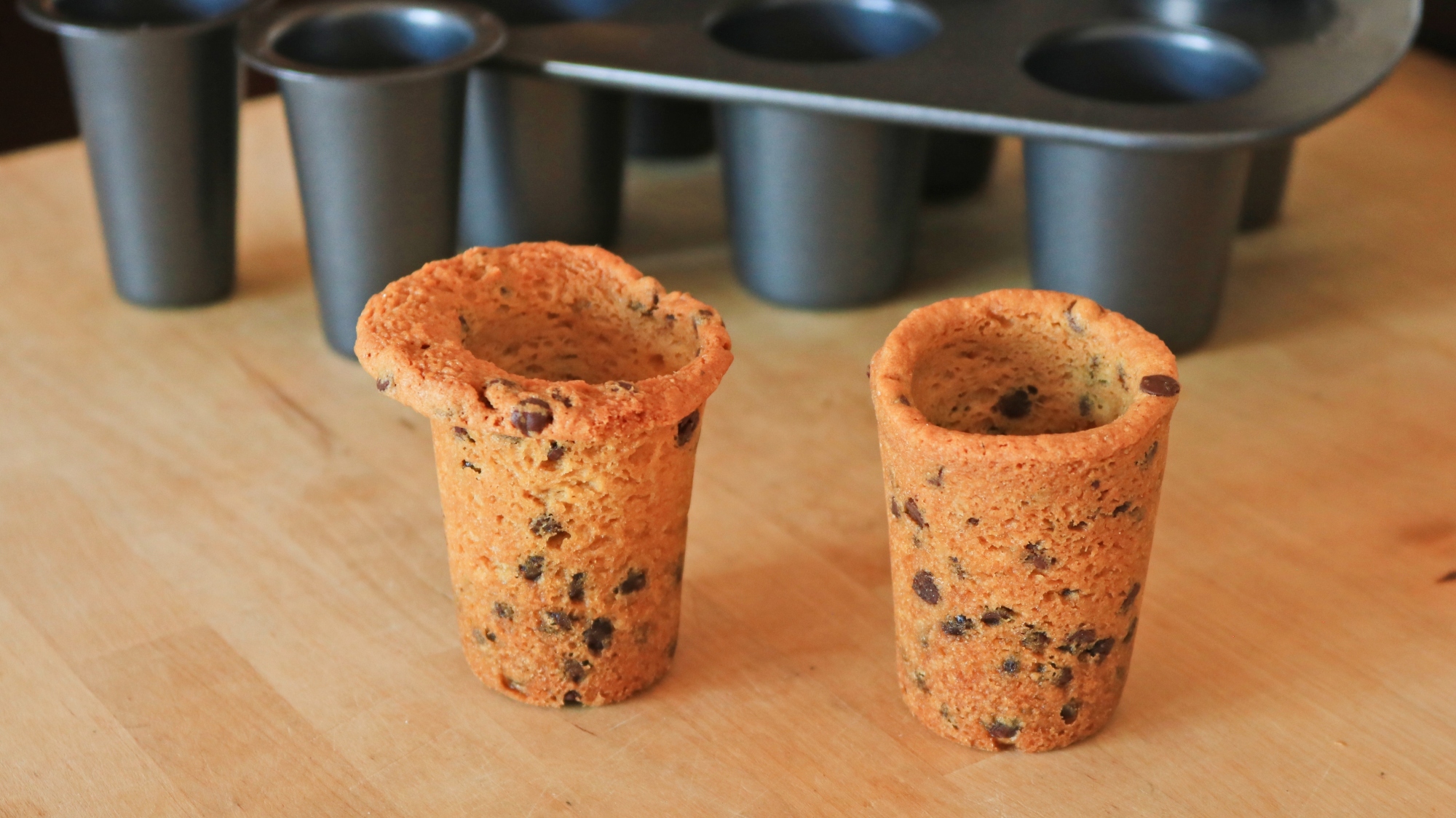 Two cookie shot glasses on a table.