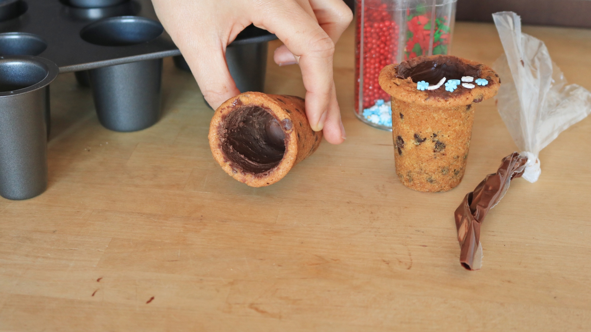 A hand holding a cookie shot glass.