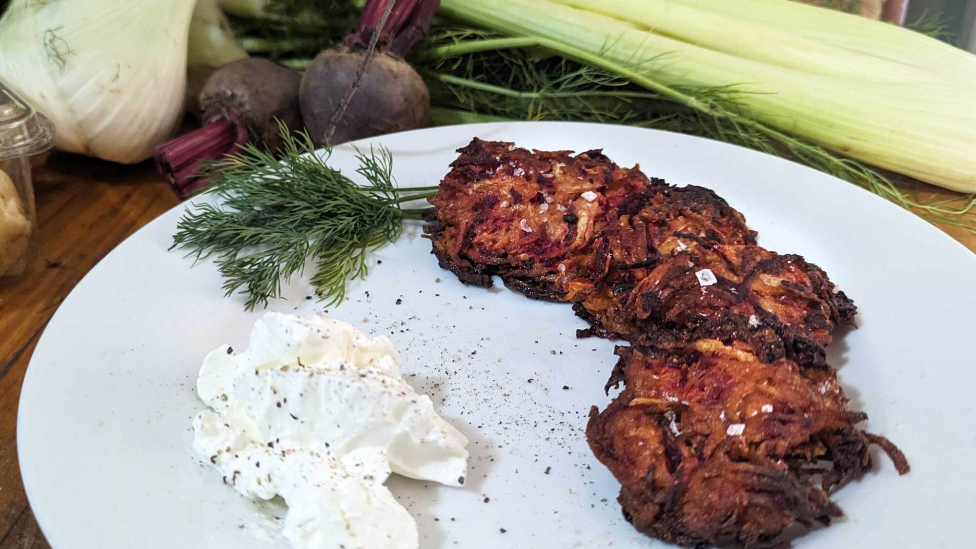 Red flannel latkes on a plate with sour cream