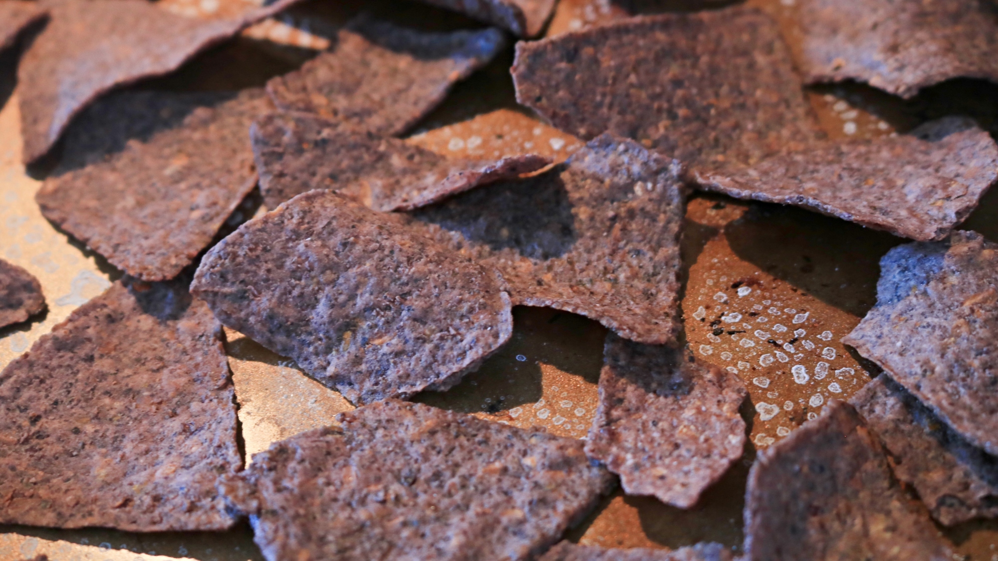 Blue corn chips on a metal sheet pan.