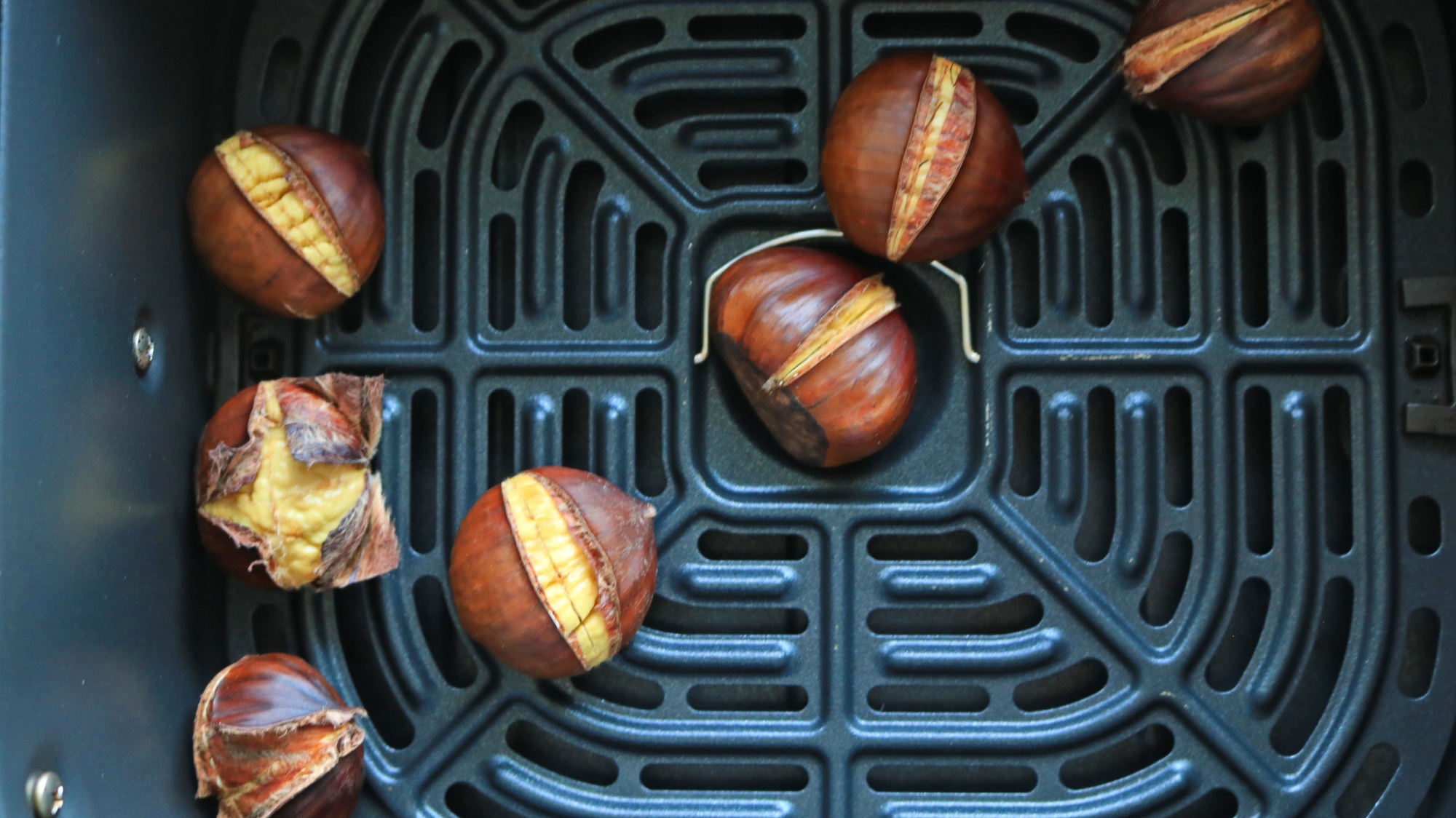 Roasted chestnuts in an air fryer basket.