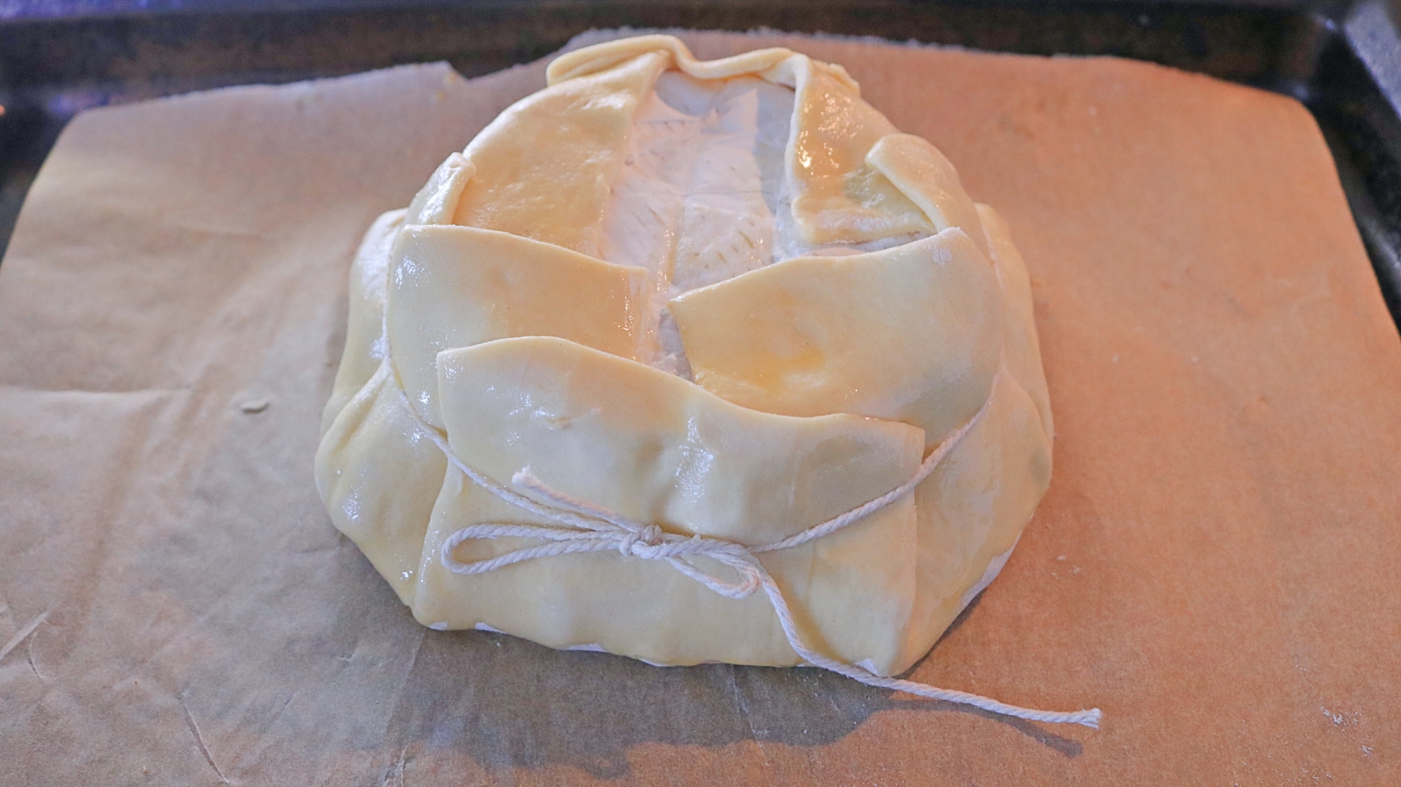 Puff pastry around a wheel of brie and wrapped with kitchen string.