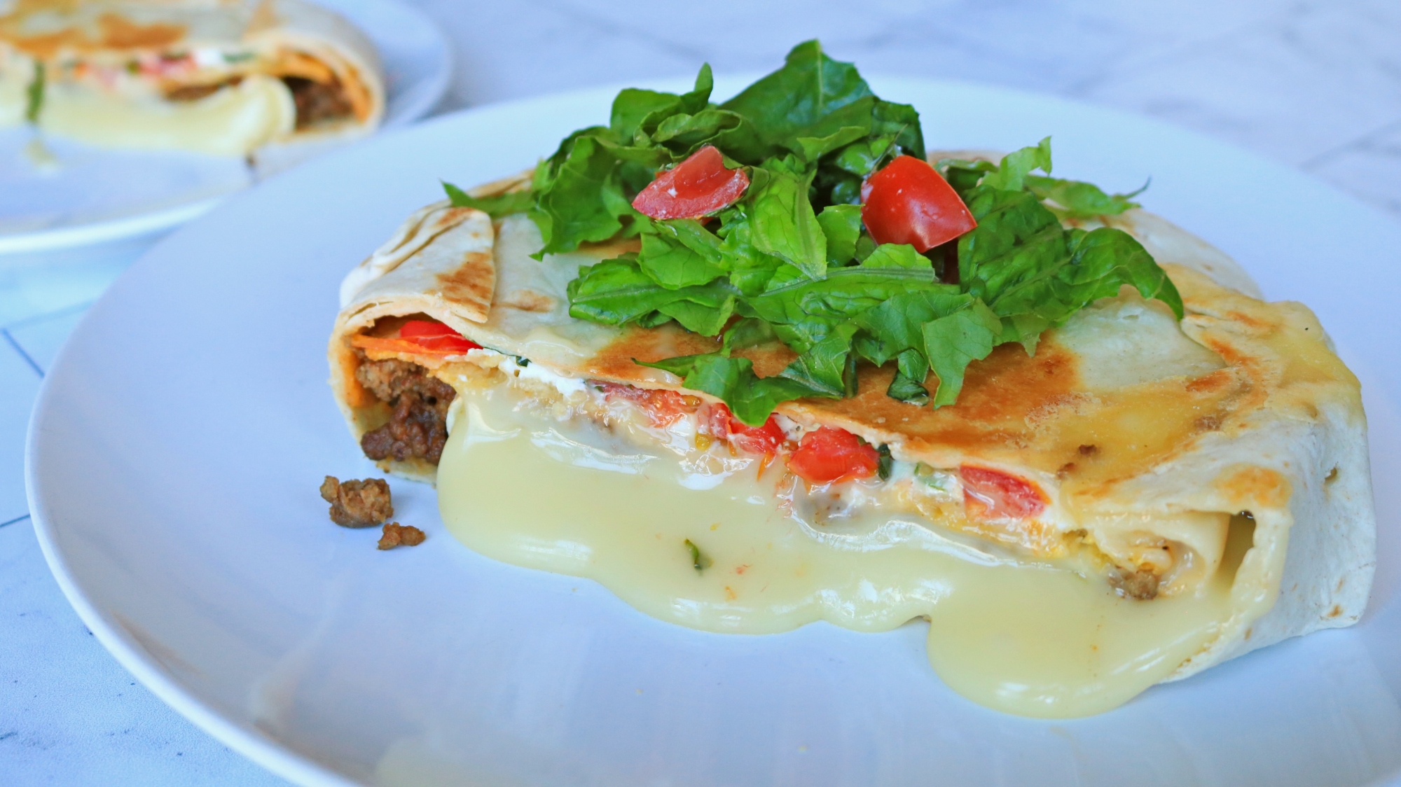 A sliced Crunchwrap Supreme baked brie oozing onto the plate.