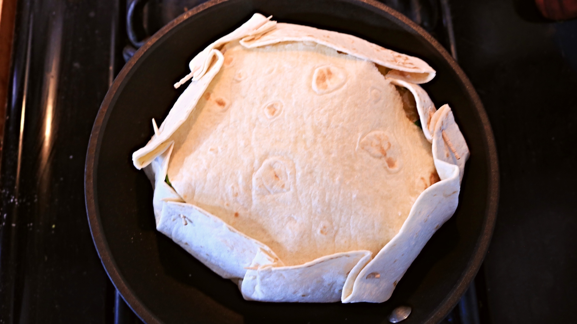 Flour tortilla with toothpicks securing pleats around the edges.