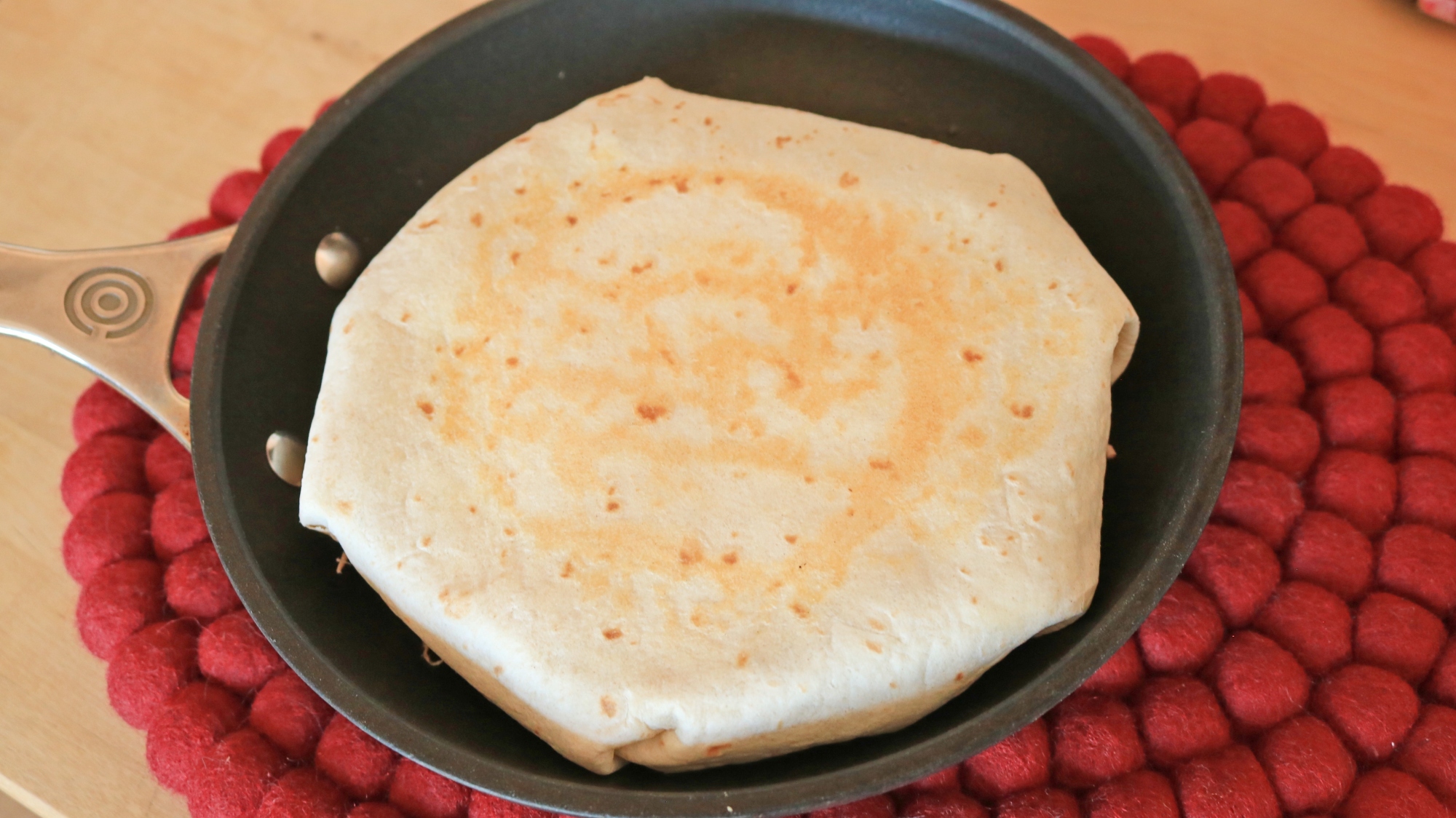 A folded tortilla in a frying pan. 