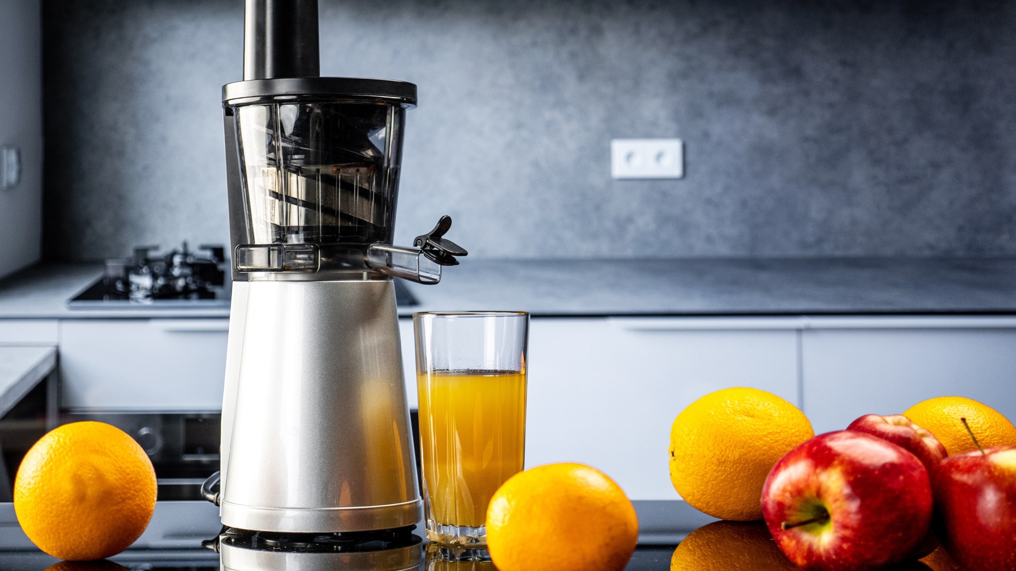 An electric juicer surrounded by fruits