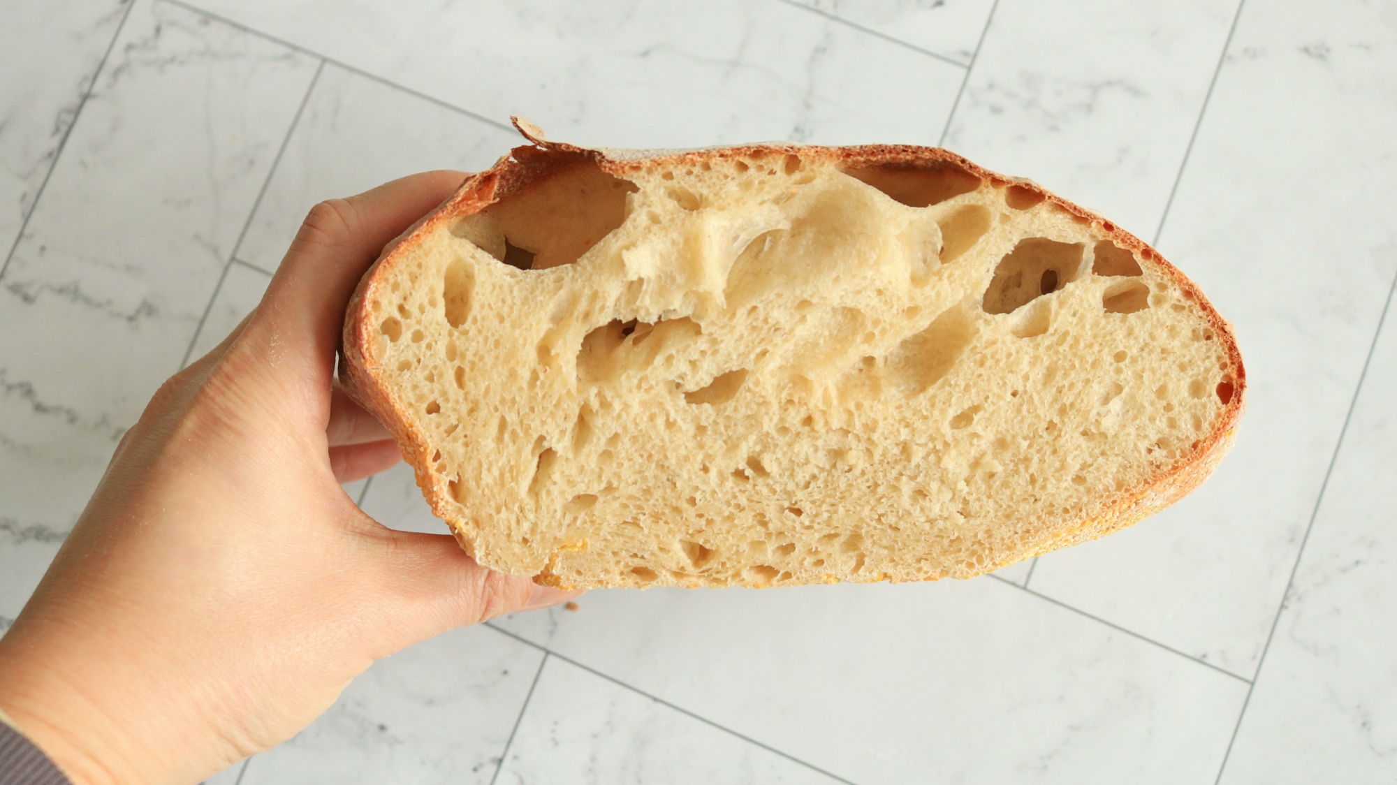 Irregular loaf of bread sliced in half.