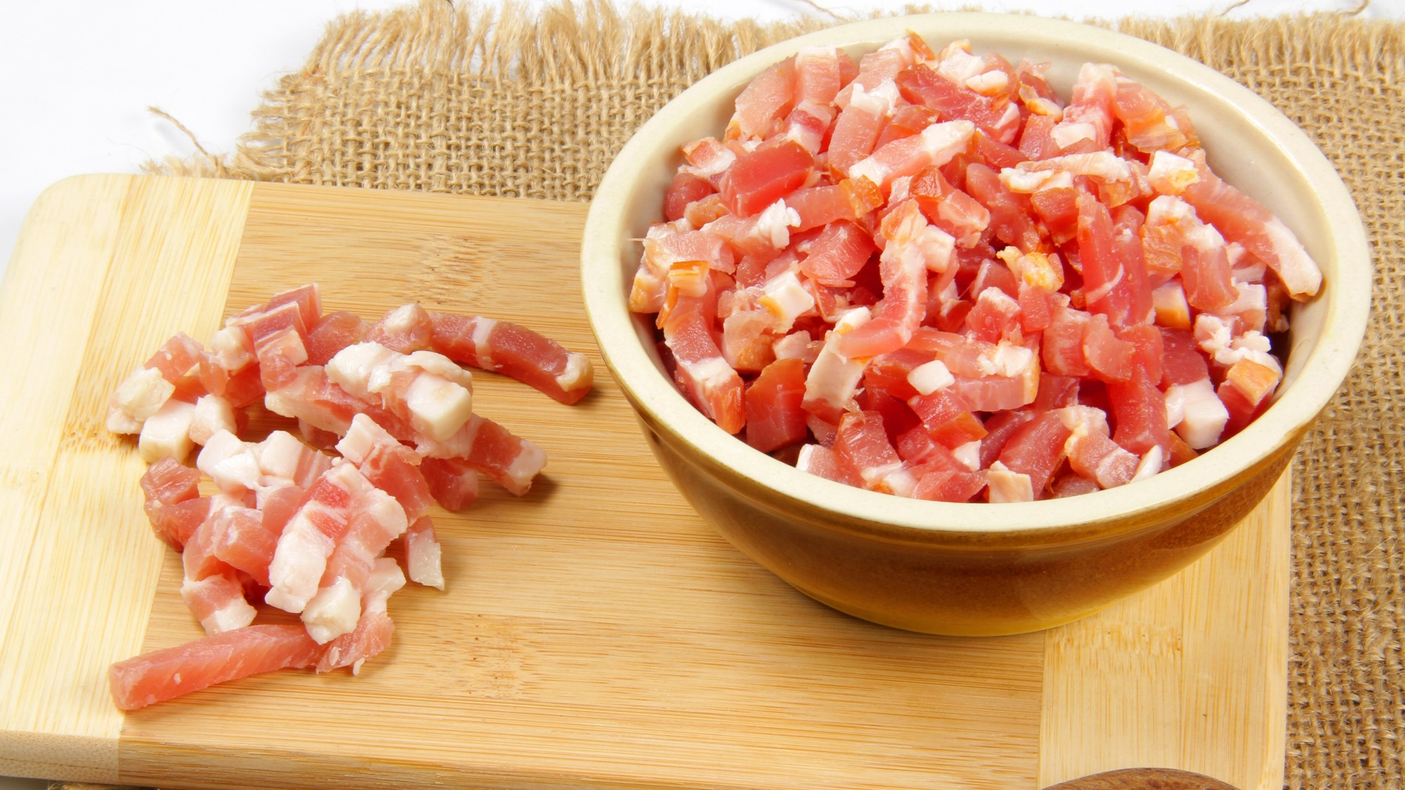 Raw lardons in a bowl and on a cutting board.