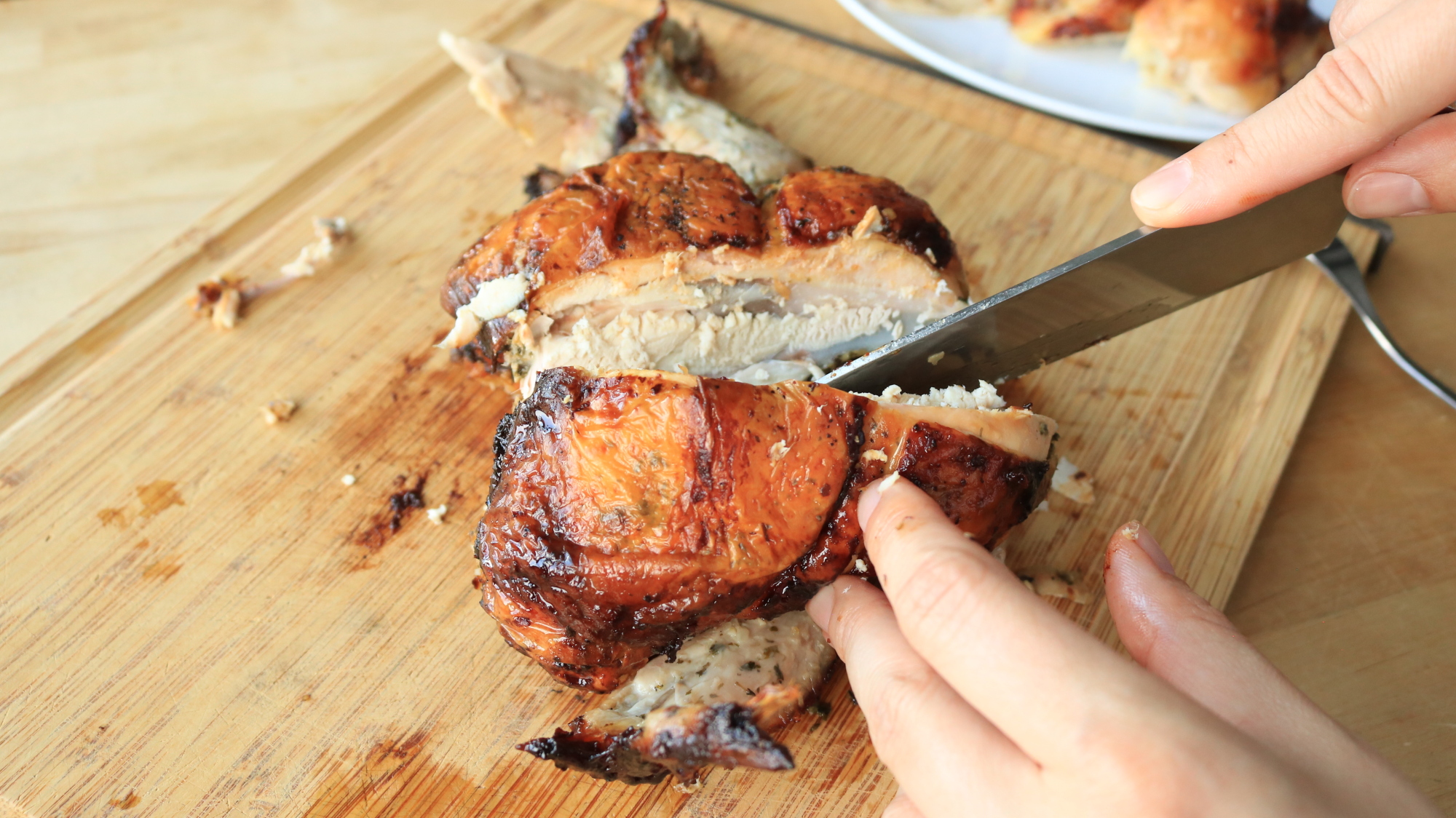 A knife carving a chicken breast.