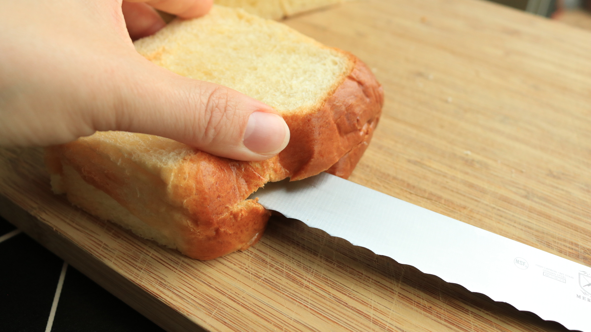 A knife slices a pocket into a wide piece of bread.