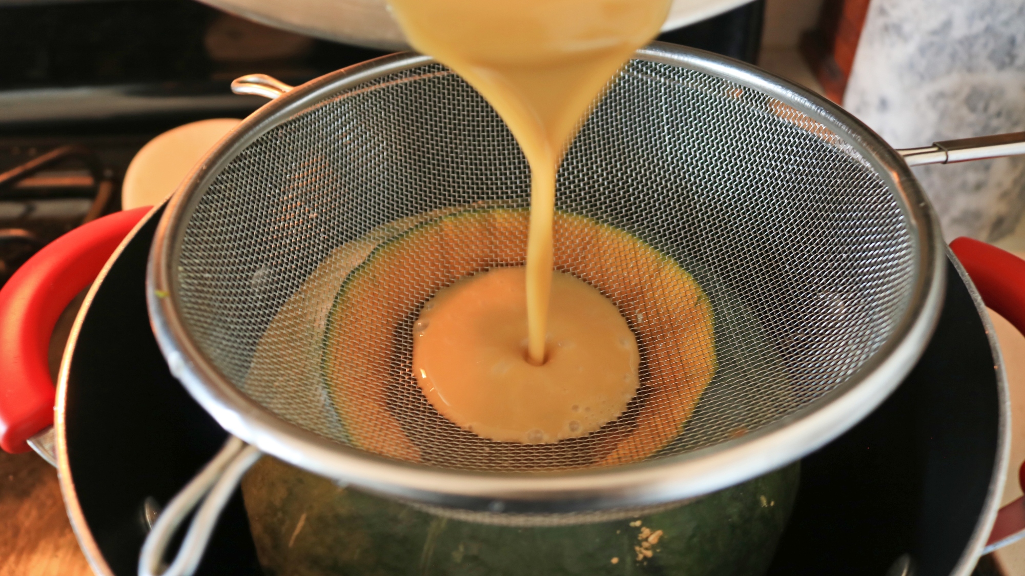 Custard being poured through a seive into the kambocha.