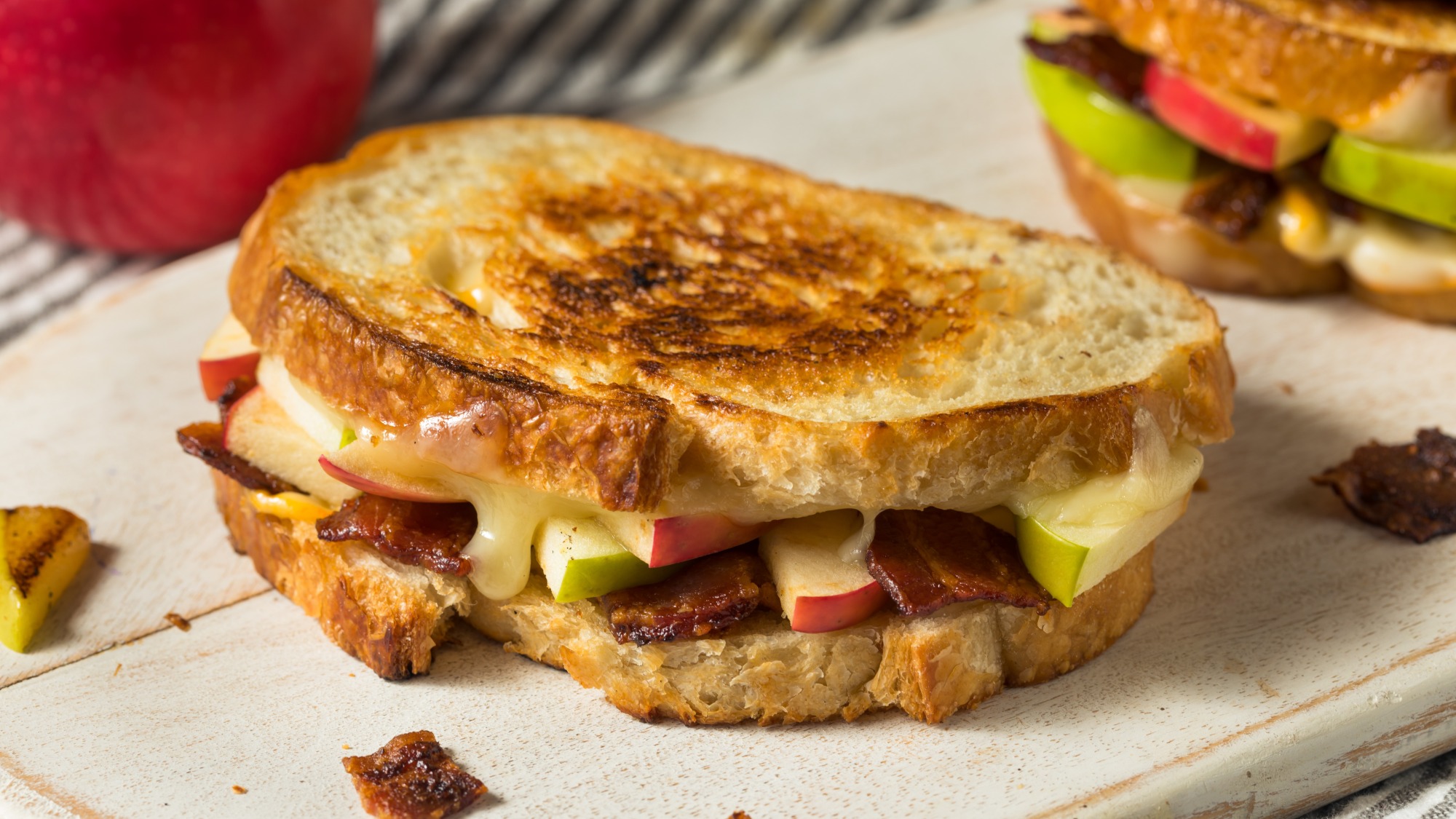 An apple and bacon sandwich with melted cheese.