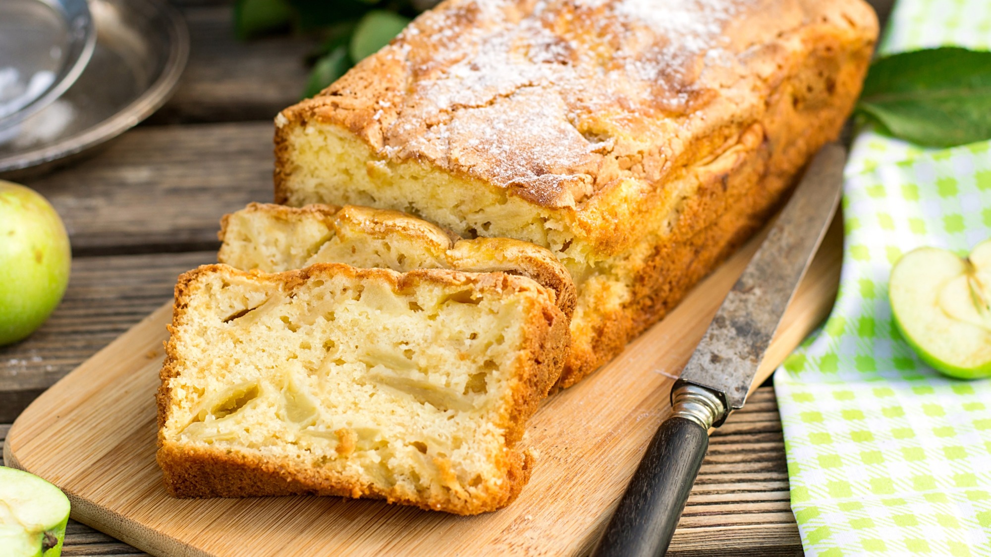 An apple cake sliced on a cutting board.