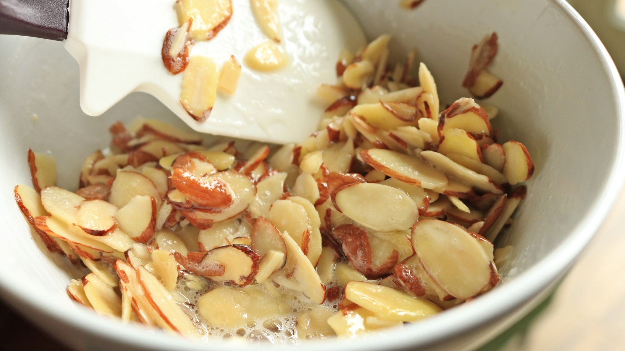 Sliced almonds in a bowl with egg whites.