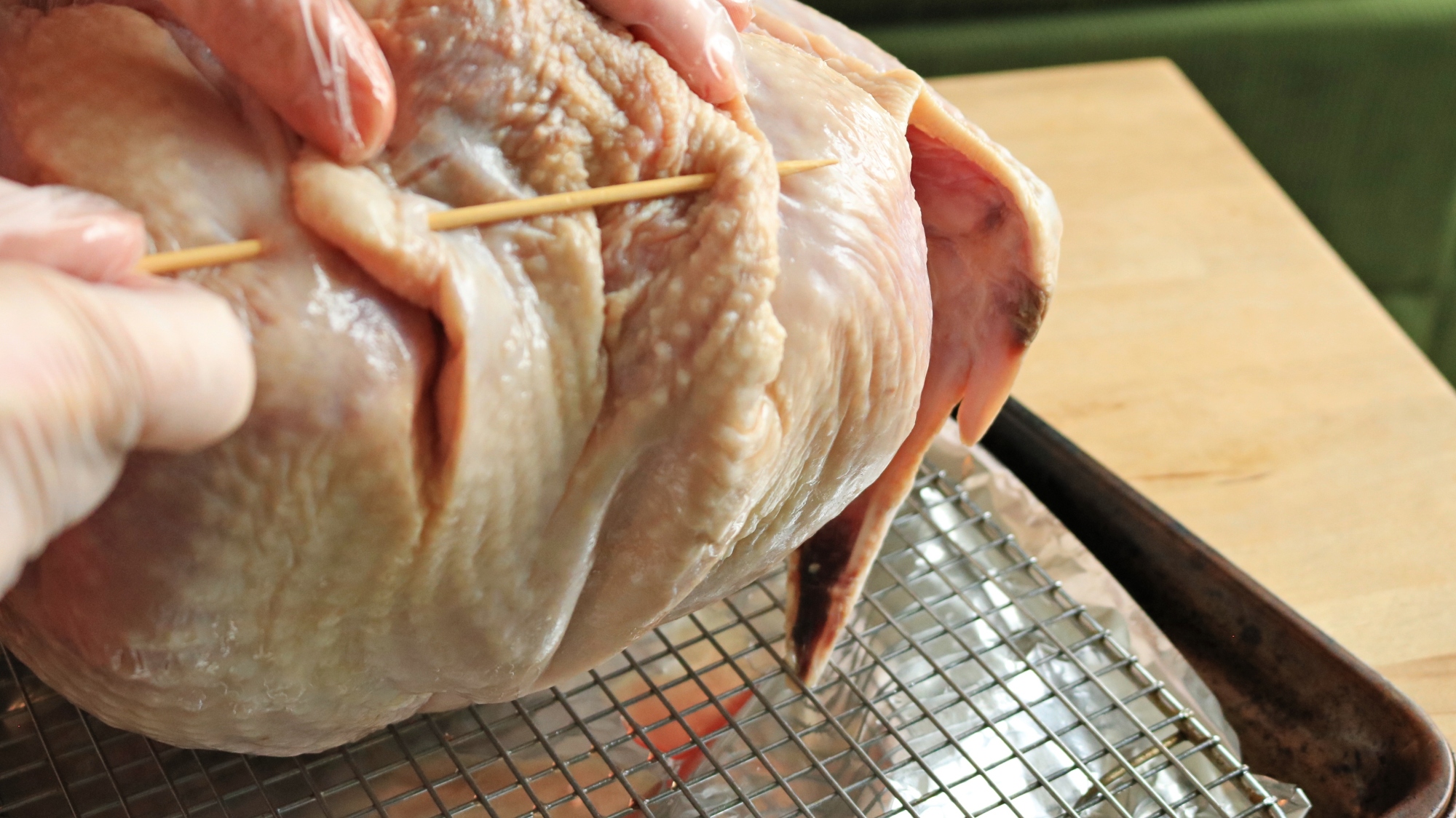 A skewer is pushed through the neck skin of the turkey and the body.