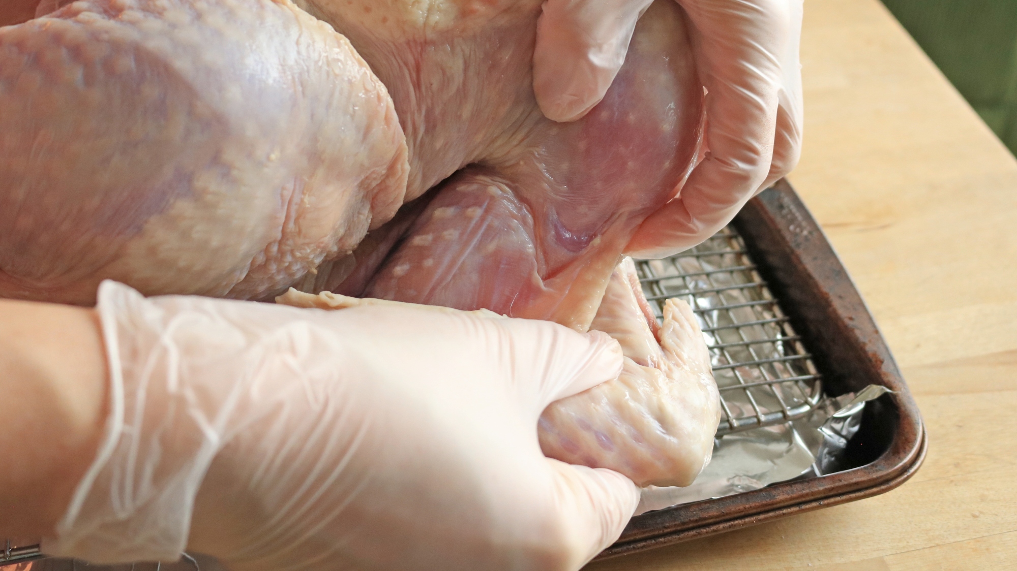 Hands tucking the turkey's wing behind the back.